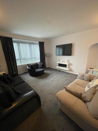 a living room with a couch and a tv at Amazing Alps and Loch views - HOT TUB and pet friendly in Arrochar
