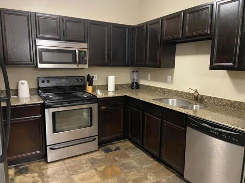 a kitchen with brown cabinets and a stove and a sink at Resort Style Apt/Home in Houston Medical Centre in Houston