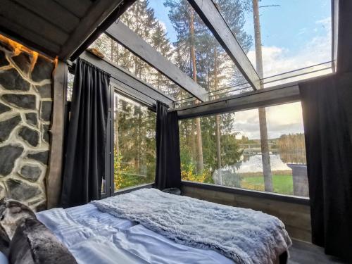 a bedroom with a bed in front of a window at Glass Igloos by the water - Lasisviitit in Laukaa