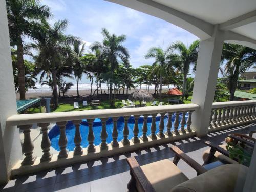 a balcony with a view of the beach and palm trees at Hermosa Beach House in Playa Hermosa