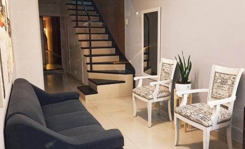 a living room with a couch and two chairs and a staircase at Hotel Miceli in Bragado
