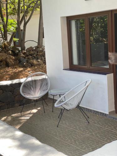 two white chairs and a table next to a building at Apartamentos Finca Wapa in Frontera