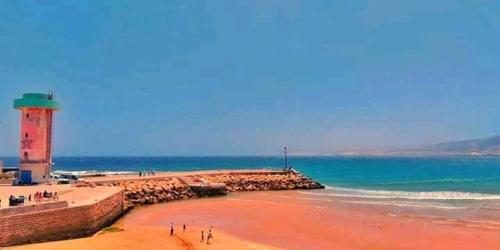 a beach with a lighthouse and people on the beach at Brothers House 2 in Imsouane