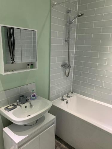 a white bathroom with a sink and a bath tub at The Cochno Flat, Clydebank in Dalmuir