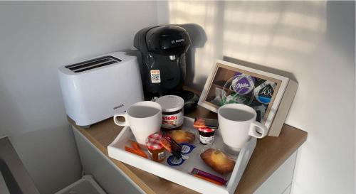 a counter with cups and a coffee maker on it at Petit cocon proche gare et commerces in Chantilly