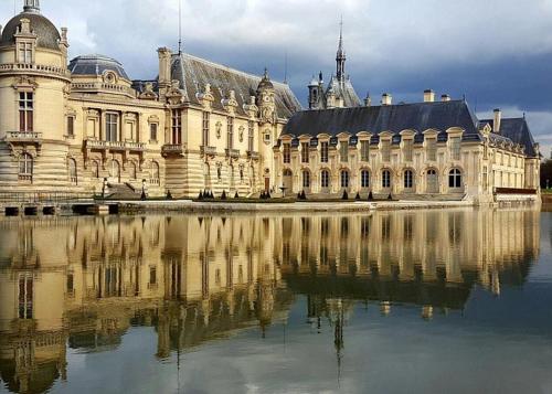 a large building with its reflection in the water at Petit cocon proche gare et commerces in Chantilly