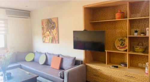 a living room with a couch and a flat screen tv at Appartement avec piscine a 150m des jardins Majorelle in Marrakech