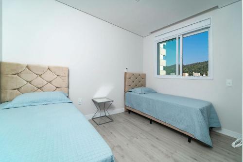 a bedroom with two beds and a window at Lindo Apartamento com 2 suítes e piscina em Bombas 705 in Bombas