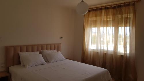 a bedroom with a bed with white sheets and a window at The Apartments in VALAMAR in Hamallë