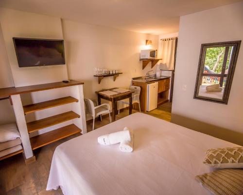 a hotel room with a bed and a kitchen at Pousada Capitão Cook in Praia do Rosa
