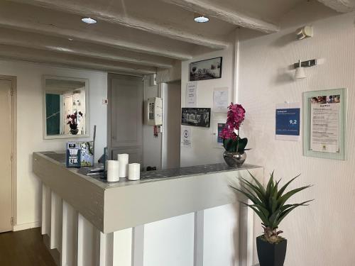 a reception counter in a room with flowers on the wall at Logis Hôtel Castel de Mirambel in Lourdes