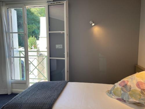 a bedroom with a bed and a large window at Logis Hôtel Castel de Mirambel in Lourdes