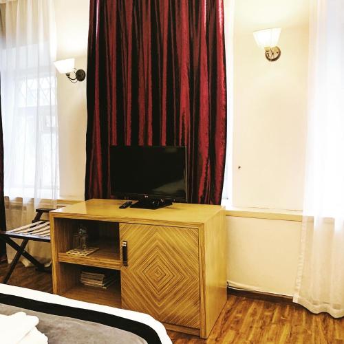 モスクワにあるSleepy Tom Boutique Hotelの窓の前に位置する木製キャビネットの上にテレビ付きのベッドルーム1室