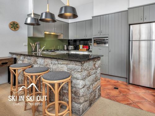 a kitchen with a stone counter and stools in it at Ski In Ski Out 16 in Thredbo