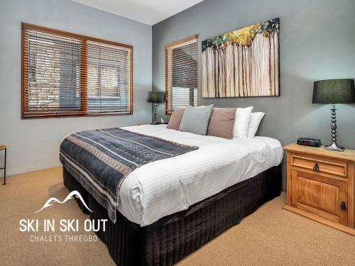 a bedroom with a large bed and a night stand at Ski In Ski Out 16 in Thredbo