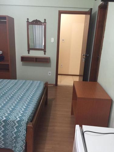 a bedroom with a bed and a mirror and a table at Hotel Regência in São Lourenço