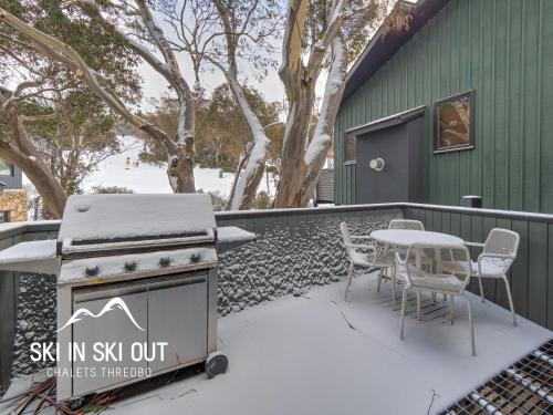 a grill with a table and chairs in the snow at Ski In Ski Out #08 in Thredbo