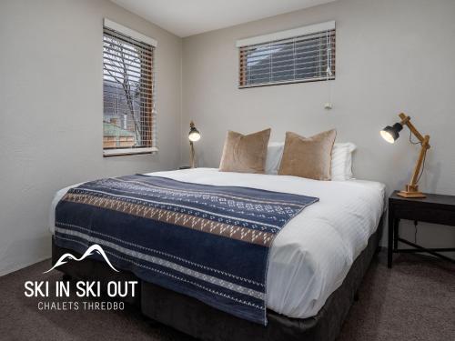 a bedroom with a bed with a blue and white blanket at Ski In Ski Out #08 in Thredbo