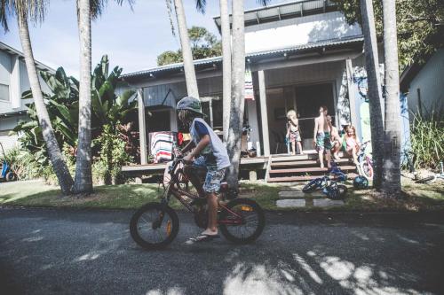 a boy is standing on a bike on the street at Mobys Beachside Retreat in Boomerang Beach
