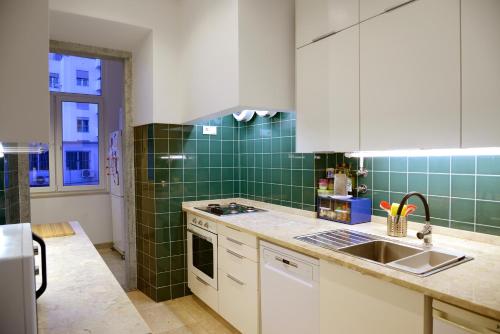リスボンにあるMy Apartmentの緑のタイル張りの壁、シンクが備わるキッチン