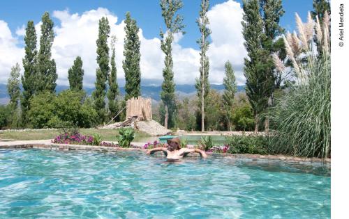 una donna in una piscina in un giardino con alberi di Finca Huayrapuca a Famatina