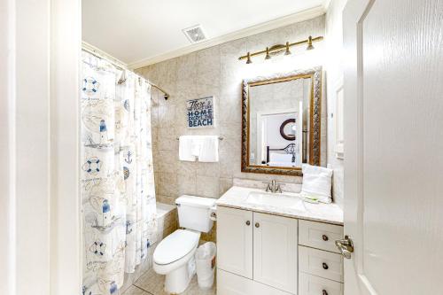 a bathroom with a toilet and a sink and a mirror at Emerald Shores Cottage in Destin