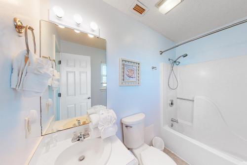 uma casa de banho branca com uma banheira, um lavatório e um WC. em The Rusty Pelican em Gulf Shores