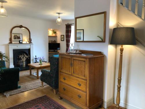 a living room with a dresser and a mirror at Glenmuir Cottage in Dornoch