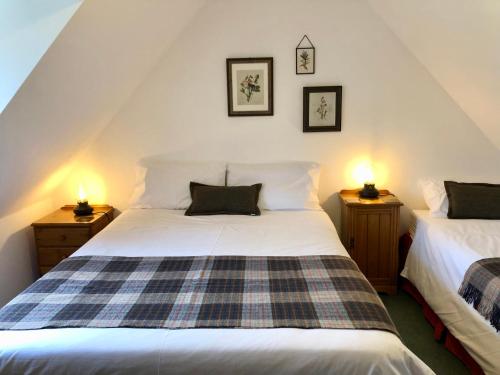 a bedroom with two beds and two lamps on night stands at Glenmuir Cottage in Dornoch