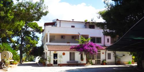 a white building with purple flowers on it at Residenza Collina Dei Pini in Vieste