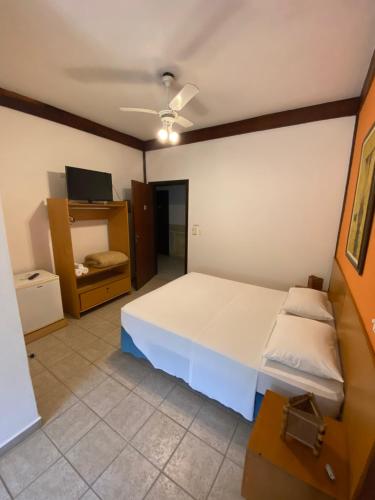 a bedroom with a large white bed and a tv at Pousada Samburá in Barra do Una