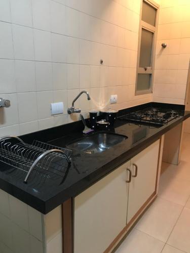 a kitchen counter with a sink and a mirror at Apto Alemanha no centro de Ribeirão Preto SP in Ribeirão Preto