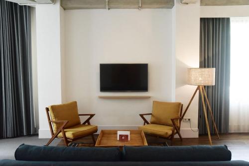 a living room with a couch and chairs and a tv at Hotel Monopoli in Jakarta