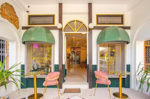 Isara Boutique Hotel and Cafe في فوكيت تاون: واجهة متجر مع طاولتين وكراسي وردية