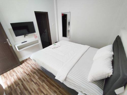 a bedroom with a white bed and a flat screen tv at Maita Homestay Ringroad Utara Mitra RedDoorz in Kejayan