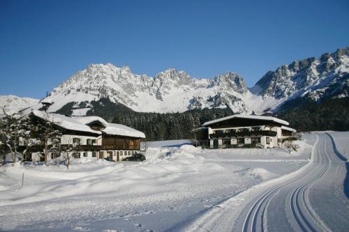 a snow covered mountain with houses and a road at Pension Sunnbichl in Going