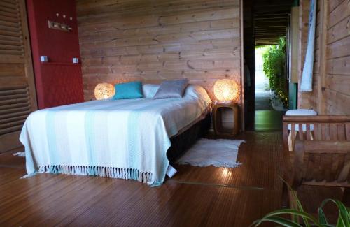 1 dormitorio con 1 cama y pared de madera en Heliconia 1 ou 2 chambres, cuisine, terrasse, piscine partagée, 2 à 4 personnes, en Étang-Salé