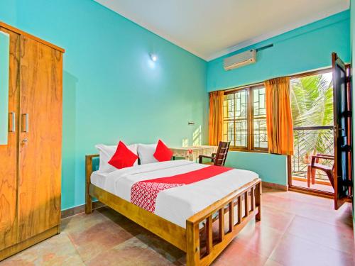 a bedroom with a bed with blue walls and a window at Aaram Beach Resort in Kannur