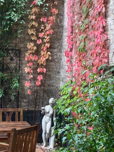 een standbeeld naast een muur met bloemen bij Hotel Gunia in Berlijn