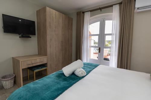 a bedroom with a bed with a television and a window at Caribbean Estates - 35 Montego Bay by Luxe in Port Edward