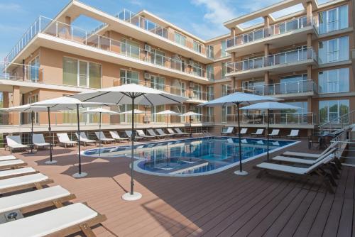 a hotel with a swimming pool with chairs and umbrellas at Santa Maria Apartments in Ahtopol