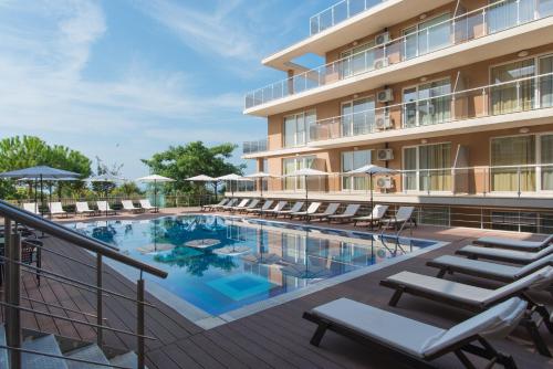 a swimming pool with lounge chairs next to a hotel at Santa Maria Apartments in Ahtopol