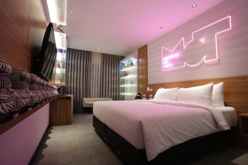 um quarto com uma cama grande e uma placa de néon na parede em Creative Restart Hotel - CARTEL Bandung em Bandung