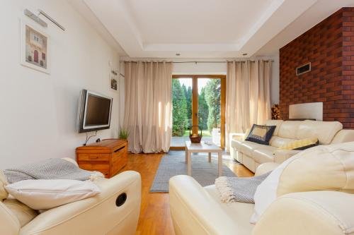 a living room with white furniture and a tv at Holiday House Cinema Experience Warsaw Michałowice by Renters in Michałowice