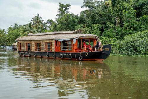 un barco con gente en él en un río en Grand Villa Houseboat, en Kumarakom