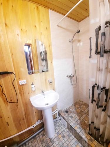 a bathroom with a white sink and a shower at House Baikal in Baykalsk
