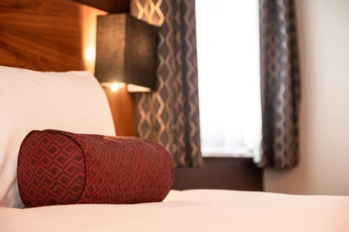 a red pillow sitting on a bed with a window at Miller & Carter Brighton by Innkeeper's Collection in Brighton & Hove