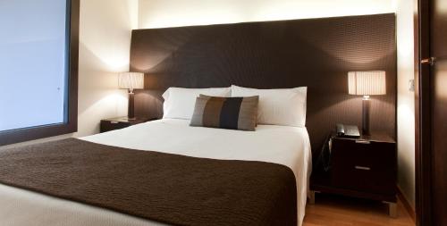 a bedroom with a large white bed with two lamps at Aparthotel Senator Barcelona in Barcelona