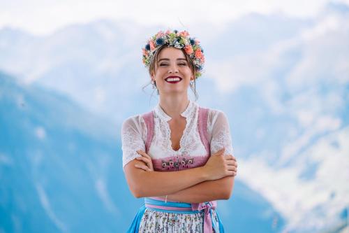 a woman wearing a flower crown standing with her arms crossed at ZillergrundRock Luxury Mountain Resort in Mayrhofen