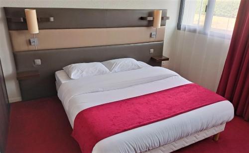 Résidence Hôtelière des Ondes في Saint-Lys: غرفة نوم بسرير كبير مع بطانية حمراء